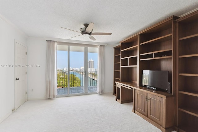unfurnished office with a textured ceiling, ceiling fan, and light colored carpet