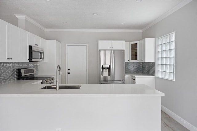kitchen with a peninsula, glass insert cabinets, a sink, stainless steel appliances, and tasteful backsplash
