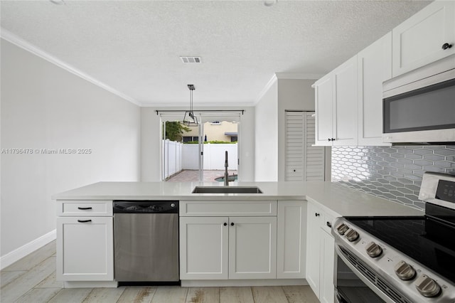 kitchen featuring a sink, ornamental molding, stainless steel appliances, and a peninsula