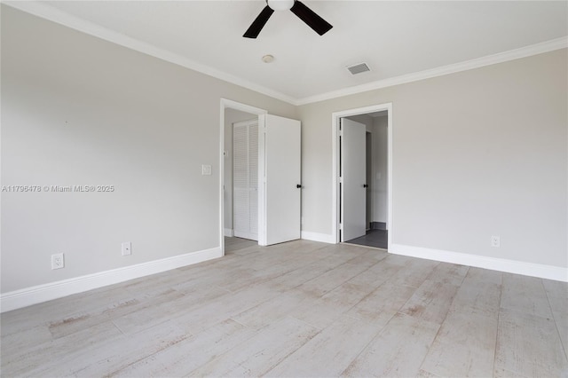 spare room featuring wood finished floors, ornamental molding, visible vents, ceiling fan, and baseboards