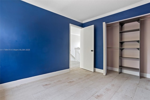 unfurnished bedroom with baseboards, ornamental molding, a closet, and wood finished floors