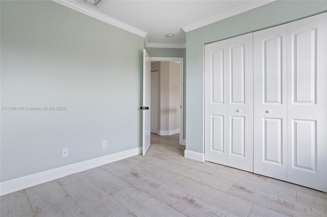 unfurnished bedroom featuring light wood finished floors, crown molding, a closet, and baseboards