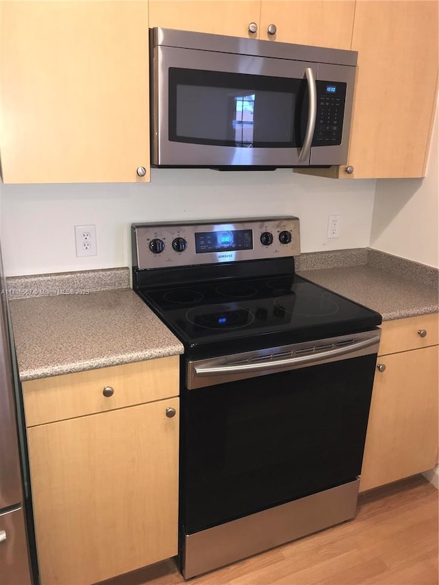 kitchen with stainless steel appliances, light wood-style flooring, and light brown cabinetry