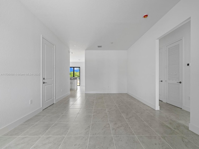 unfurnished room with baseboards and light tile patterned floors