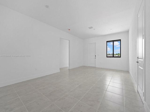spare room featuring light tile patterned flooring and baseboards