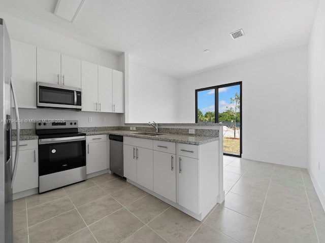 kitchen with light tile patterned flooring, visible vents, a sink, a peninsula, and stainless steel appliances