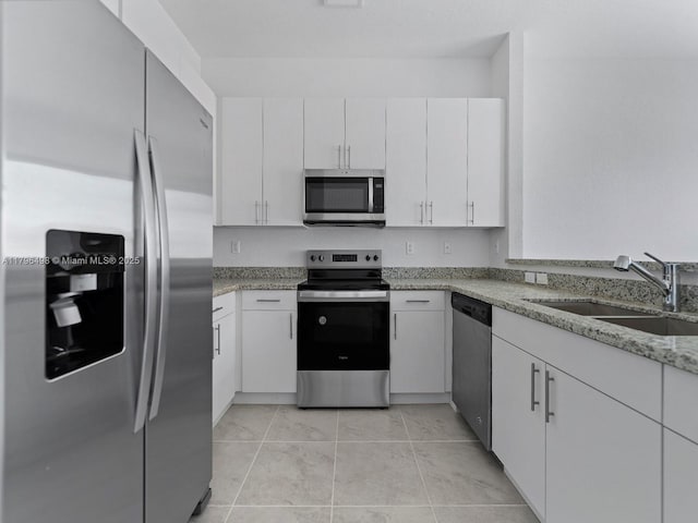 kitchen featuring a sink, stainless steel appliances, light tile patterned flooring, white cabinets, and light stone countertops