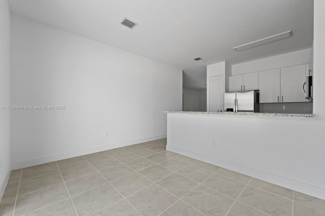 unfurnished living room with baseboards, light tile patterned floors, and visible vents