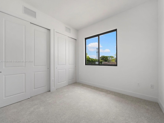 unfurnished bedroom with carpet flooring, baseboards, and visible vents