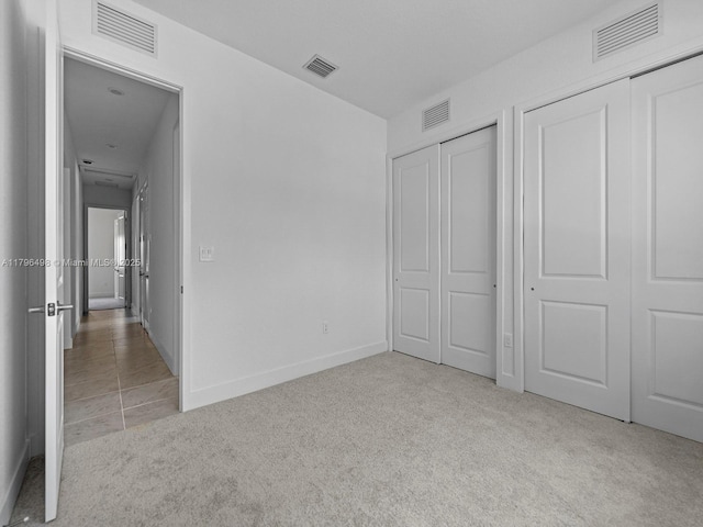 unfurnished bedroom with two closets and visible vents
