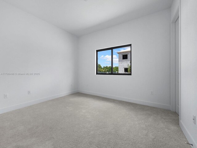 empty room with light colored carpet and baseboards