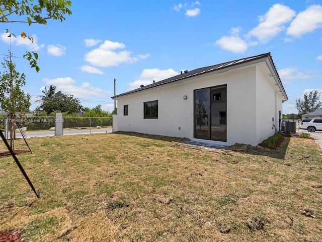 back of house featuring a yard, fence, and stucco siding