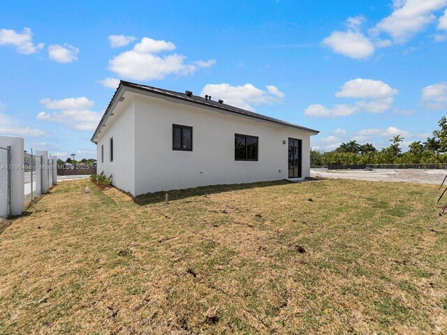 rear view of property with a yard, stucco siding, and a fenced backyard