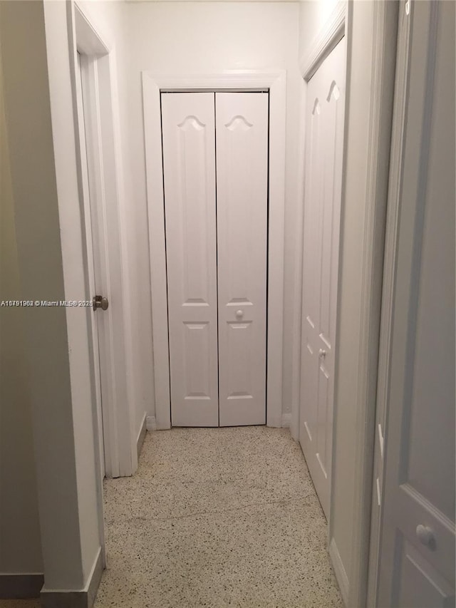 hall with baseboards and speckled floor
