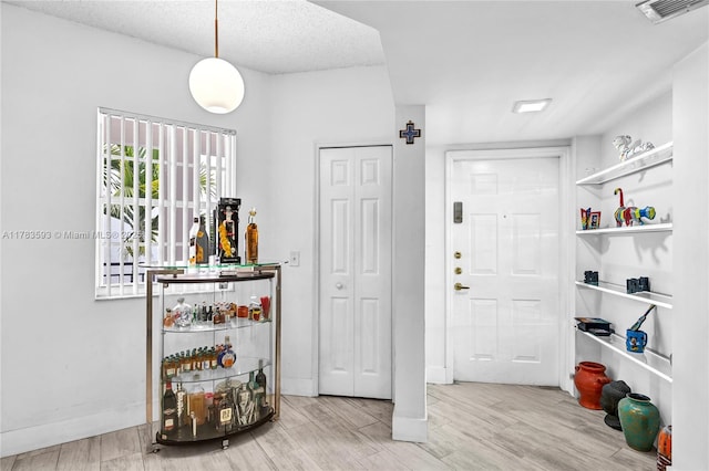 foyer with baseboards, visible vents, and wood finished floors