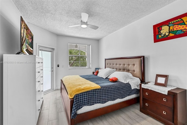 bedroom with light wood-style flooring, ceiling fan, and a textured ceiling