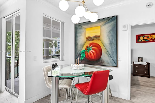 dining space with baseboards, a chandelier, crown molding, and wood finished floors