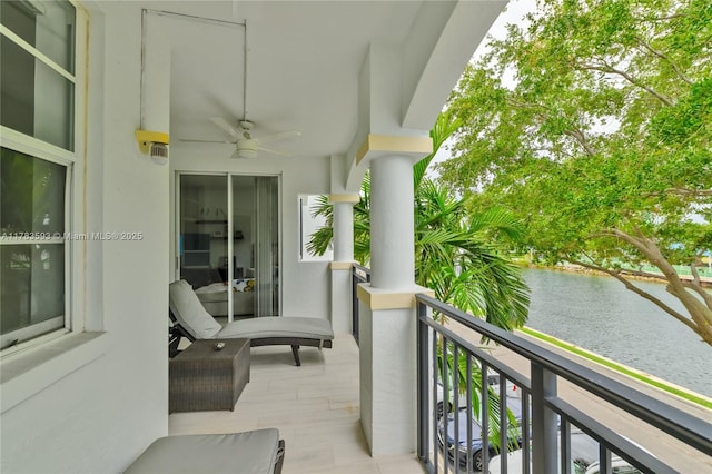 balcony featuring a water view and ceiling fan