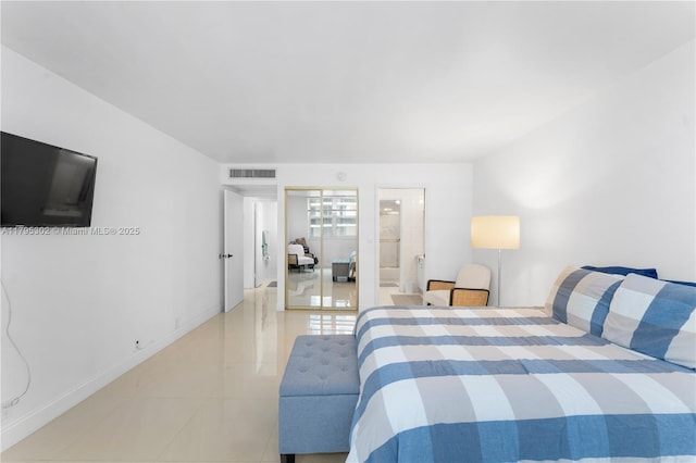 bedroom with connected bathroom, light tile patterned floors, and visible vents