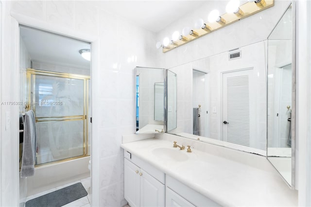 full bathroom featuring tile walls, enclosed tub / shower combo, vanity, and visible vents