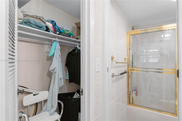 interior space featuring a walk in closet and shower / bath combination with glass door