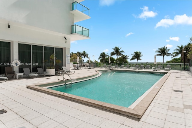 community pool with a patio area and fence