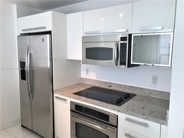 kitchen with modern cabinets, light stone countertops, white cabinets, and appliances with stainless steel finishes