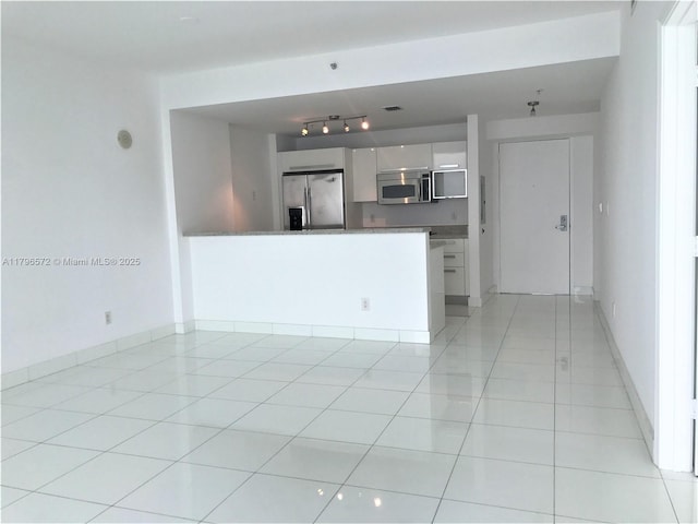 unfurnished living room featuring rail lighting, light tile patterned floors, and baseboards