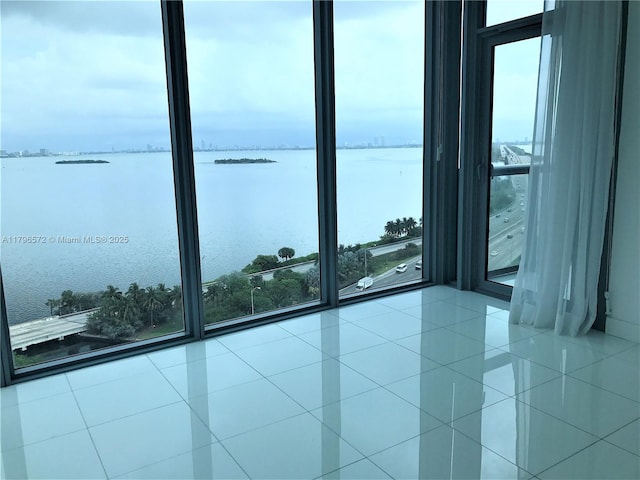 unfurnished room with tile patterned flooring, a water view, and a wealth of natural light