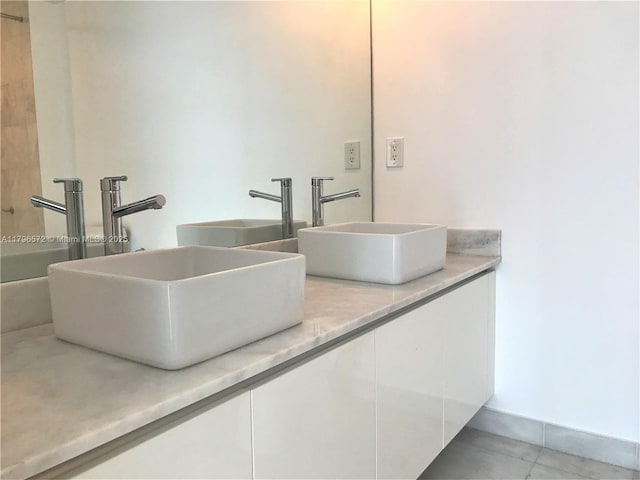 full bathroom featuring double vanity, tile patterned flooring, and a sink