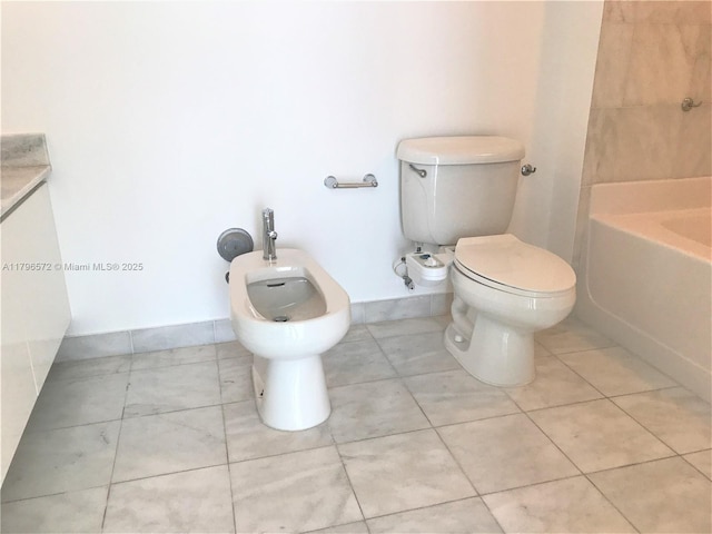 full bathroom featuring toilet, a bathing tub, a bidet, baseboards, and tile patterned flooring