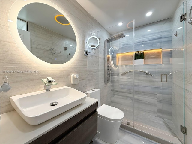 full bathroom with tile walls, toilet, a shower stall, and vanity
