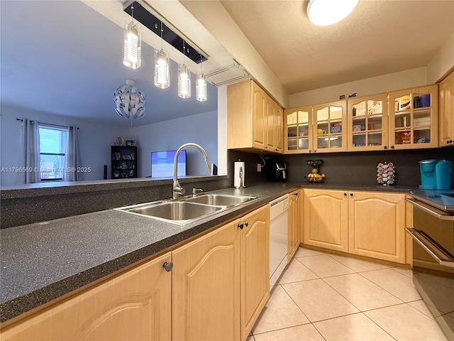 kitchen featuring white dishwasher, dark countertops, light brown cabinetry, and a sink