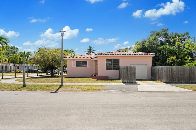 view of front facade featuring fence, concrete driveway, a garage, stucco siding, and a tiled roof