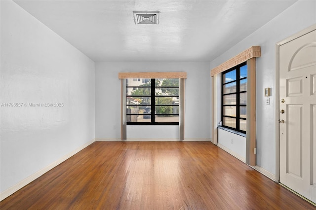 spare room with visible vents, wood finished floors, and baseboards