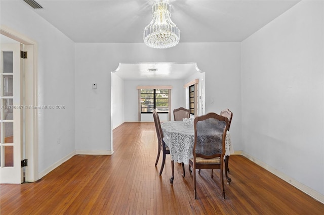 dining room featuring baseboards, a chandelier, visible vents, and wood finished floors