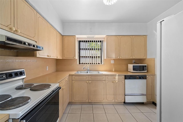kitchen featuring under cabinet range hood, white appliances, light brown cabinets, and a sink