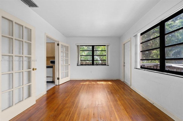unfurnished room featuring baseboards, french doors, visible vents, and wood finished floors
