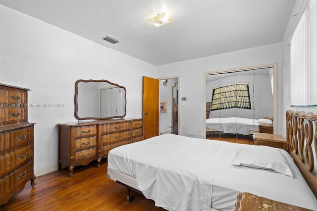 bedroom featuring a closet, baseboards, visible vents, and wood finished floors