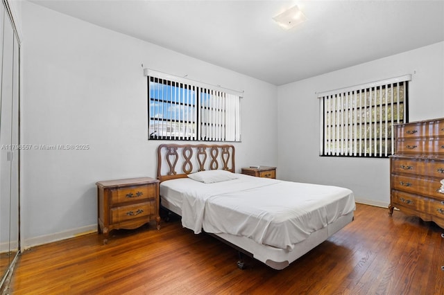bedroom featuring baseboards, multiple windows, and wood finished floors