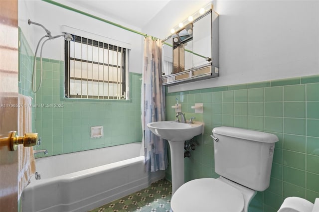 bathroom with a wainscoted wall, toilet, tile walls, and shower / bath combination with curtain