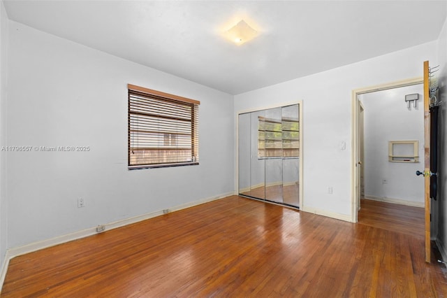 unfurnished bedroom featuring a closet, wood finished floors, and baseboards