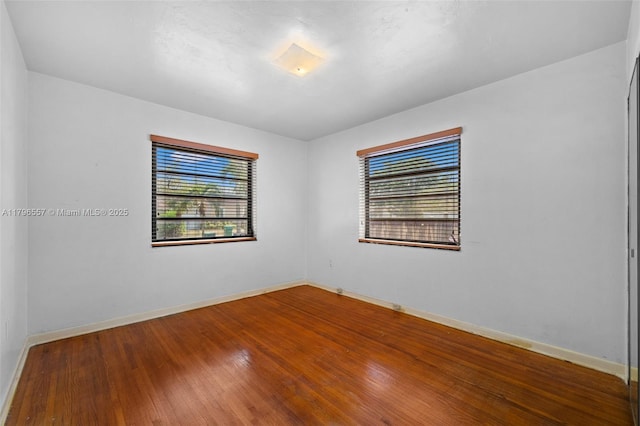 unfurnished room with hardwood / wood-style flooring and baseboards