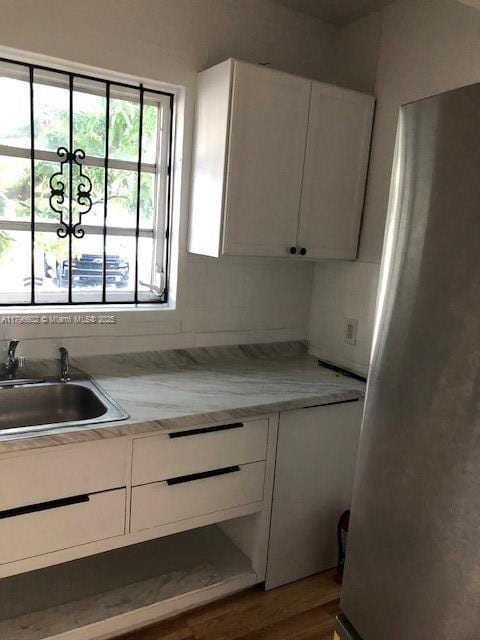 kitchen with freestanding refrigerator, dark wood-style flooring, a sink, light countertops, and white cabinets