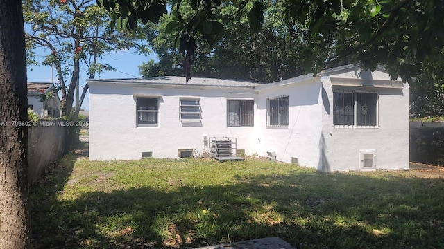 rear view of house with stucco siding, crawl space, fence, and a lawn