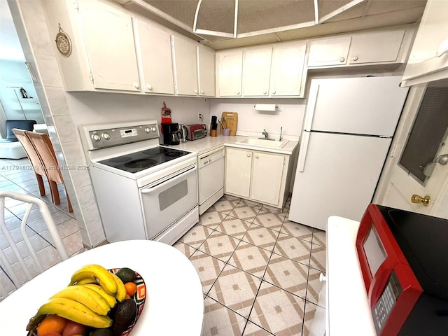 kitchen with a sink, white cabinets, white appliances, light countertops, and light tile patterned flooring