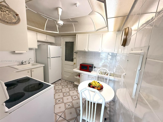 kitchen with a sink, tasteful backsplash, white appliances, light countertops, and white cabinets