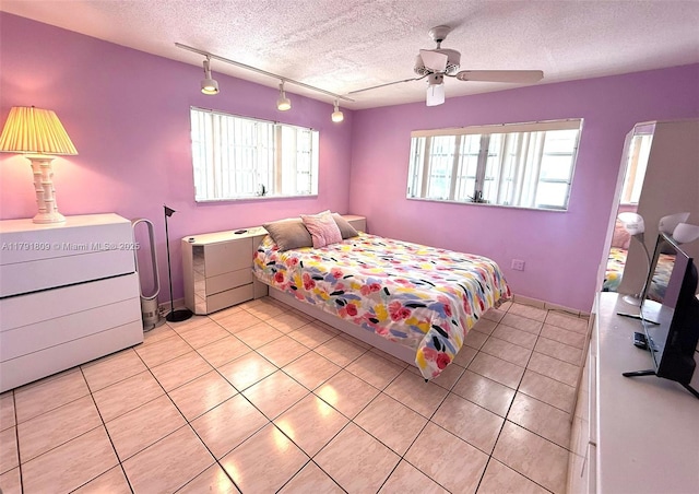 bedroom with light tile patterned floors, baseboards, a textured ceiling, and track lighting