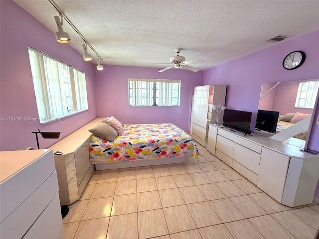bedroom featuring rail lighting, a textured ceiling, light tile patterned floors, and visible vents