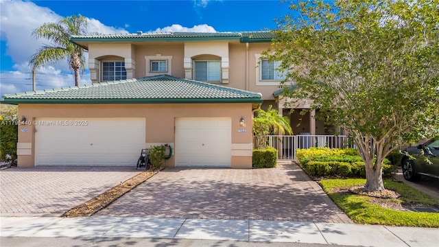 view of front of home featuring stucco siding, a tile roof, decorative driveway, and a garage